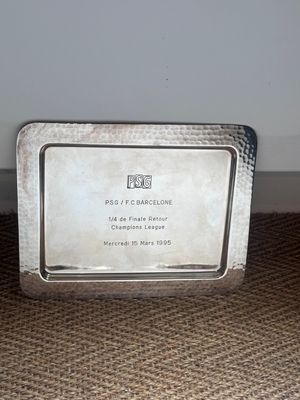 une assiette en argent ornée d'une image, posée par terre