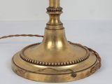 an antique brass table lamp with a glass shade and a cord