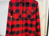 une chemise à carreaux rouges et noirs suspendue à un cintre