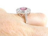 a woman ' s hand holding a ring with a pink stone