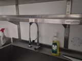a sink in a kitchen with a metal shelf above it