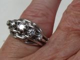 a woman ' s hand holding a silver ring with diamonds on it