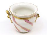 a white and pink vase with gold handles on a white surface
