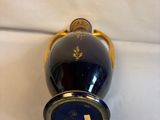 a blue vase with gold decoration on it on a white surface