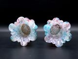 two small glass flowers with a rock in the middle