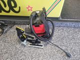 un aspirateur rouge et noir posé par terre à côté d'un panneau jaune et noir
