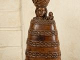 une sculpture en bois représentant une femme tenant un panier sur la tête