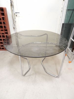 a glass table with a metal base in a room