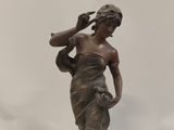 bronze statue of a woman holding a baseball bat on a marble base