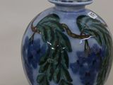 a blue vase with green leaves on it sitting on a table