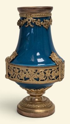 un vase bleu orné de motifs dorés sur fond blanc