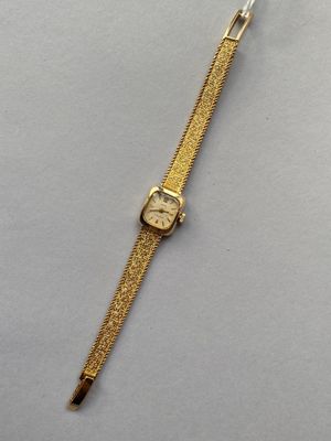 une montre en or posée sur une surface blanche