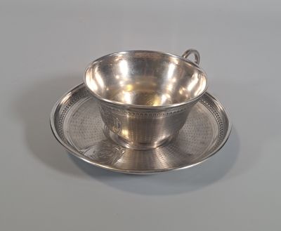 une tasse à thé ancienne en argent et sa soucoupe, posée sur une soucoupe