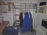 une photo d'une pièce avec un bureau, une chaise et un portant à vêtements