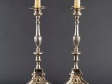 a pair of silver plated candlesticks with candles on stands