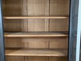 an open door to a wooden cabinet with shelves