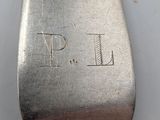 a close up of a silver spoon with the word p i engraved on it