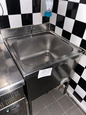 un évier en acier inoxydable dans le coin d'un mur à carreaux noirs et blancs