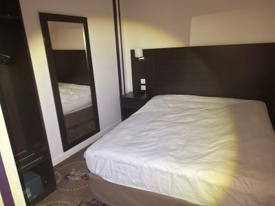 a bed with white sheets and a mirror in a room