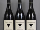 trois bouteilles de vin rouge sont alignées sur une table
