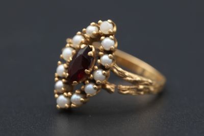 un gros plan d'une bague en or sertie de perles et de grenats