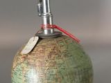 a green and brown globe with a red string on it