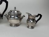 two silver plated teapots and a coffee pot on a white surface