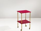 une image représentant une petite table rouge à roulettes posée sur une surface blanche