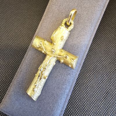 une croix en or posée sur un tissu gris, sur une table