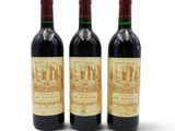 trois bouteilles de vin rouge posées l'une à côté de l'autre sur une surface blanche
