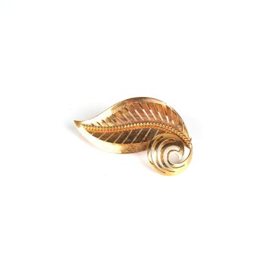 broche en feuille d'or avec un motif en spirale sur fond blanc