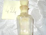 un petit flacon de parfum posé sur une table, avec un petit mot dessus