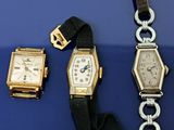 deux montres et un bracelet sont posés sur une surface bleue