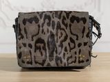 the small leopard print bag is on a wooden table