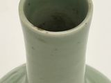 a green vase sitting on a table with a white background
