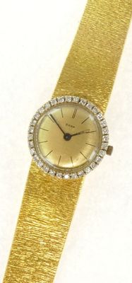 une image représentant une montre-bracelet en or dotée d'une lunette sertie de diamants