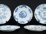 quatre assiettes bleues et blanches ornées de motifs floraux sur un fond noir