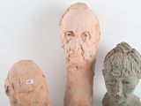 three clay heads of men sitting next to each other