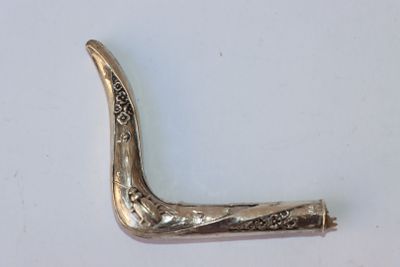 une image représentant une pipe argentée posée sur une surface blanche