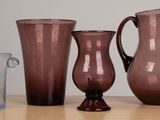 three vases and a glass sitting on a table