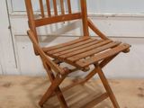 une chaise pliante en bois assise sur un sol en bois dur