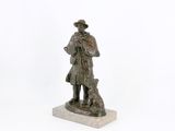 statue d'un homme accompagné d'un chien, posée sur un socle en marbre