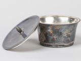 a small metal bowl with a lid on a white surface