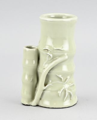 un vase blanc contenant une plante, posé sur une table