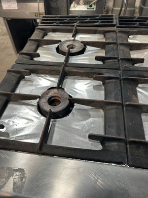 une plaque de cuisson en métal sur laquelle est posé un brûleur en métal