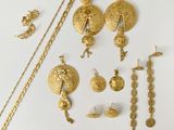 some gold jewelry on a white surface with a white background