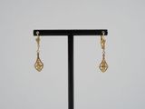 une paire de boucles d'oreilles en or posée sur un support noir