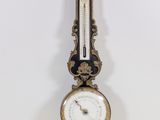 une horloge accrochée au mur, sur laquelle se trouve un baromètre