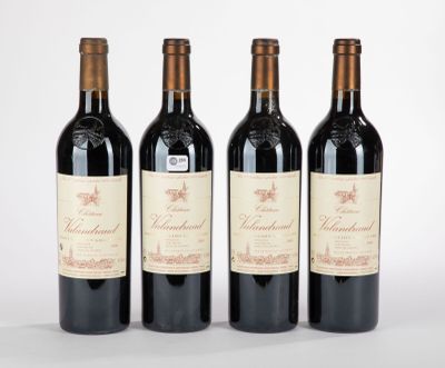 trois bouteilles de vin rouge sont alignées sur une surface blanche