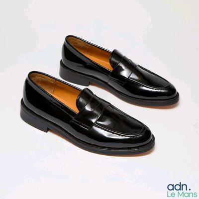 pair of black loafers on a white surface with a white background